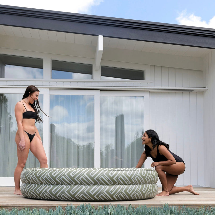 An olive green inflatable arch-shaped pool with a geometric maze pattern around the border.