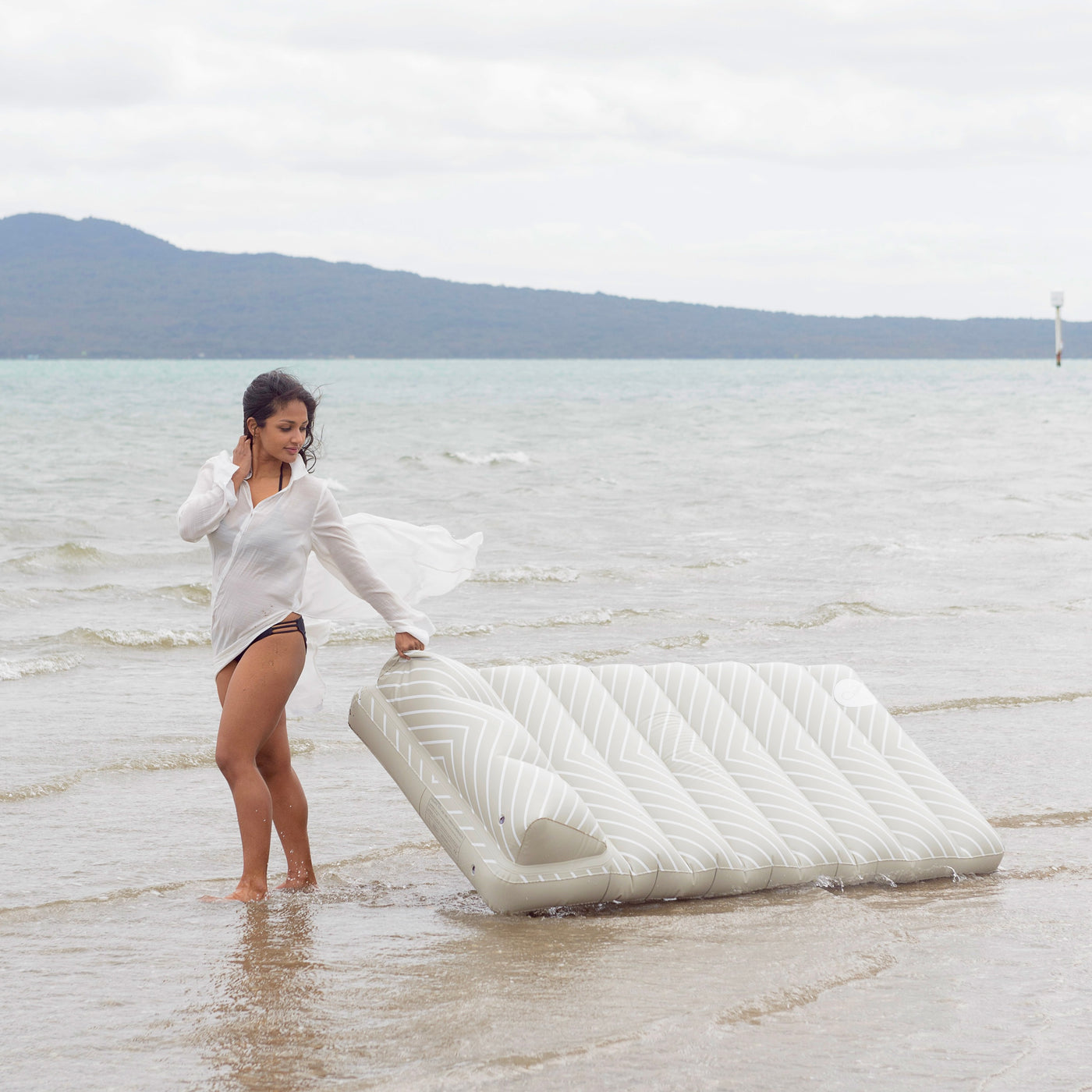 Woman carrying an inflatable lilo float on a beach