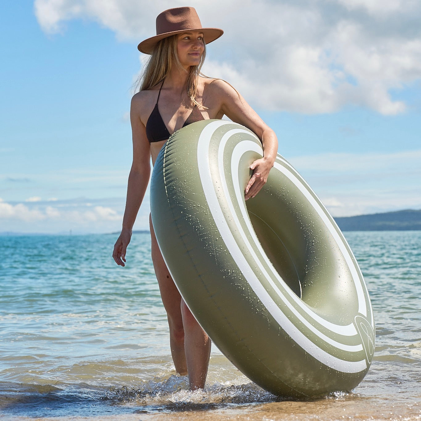 Woman holding a large inflatable ring on a beach