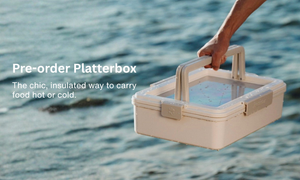 Hand holding a beige insulated platterbox with text overlay on a water background