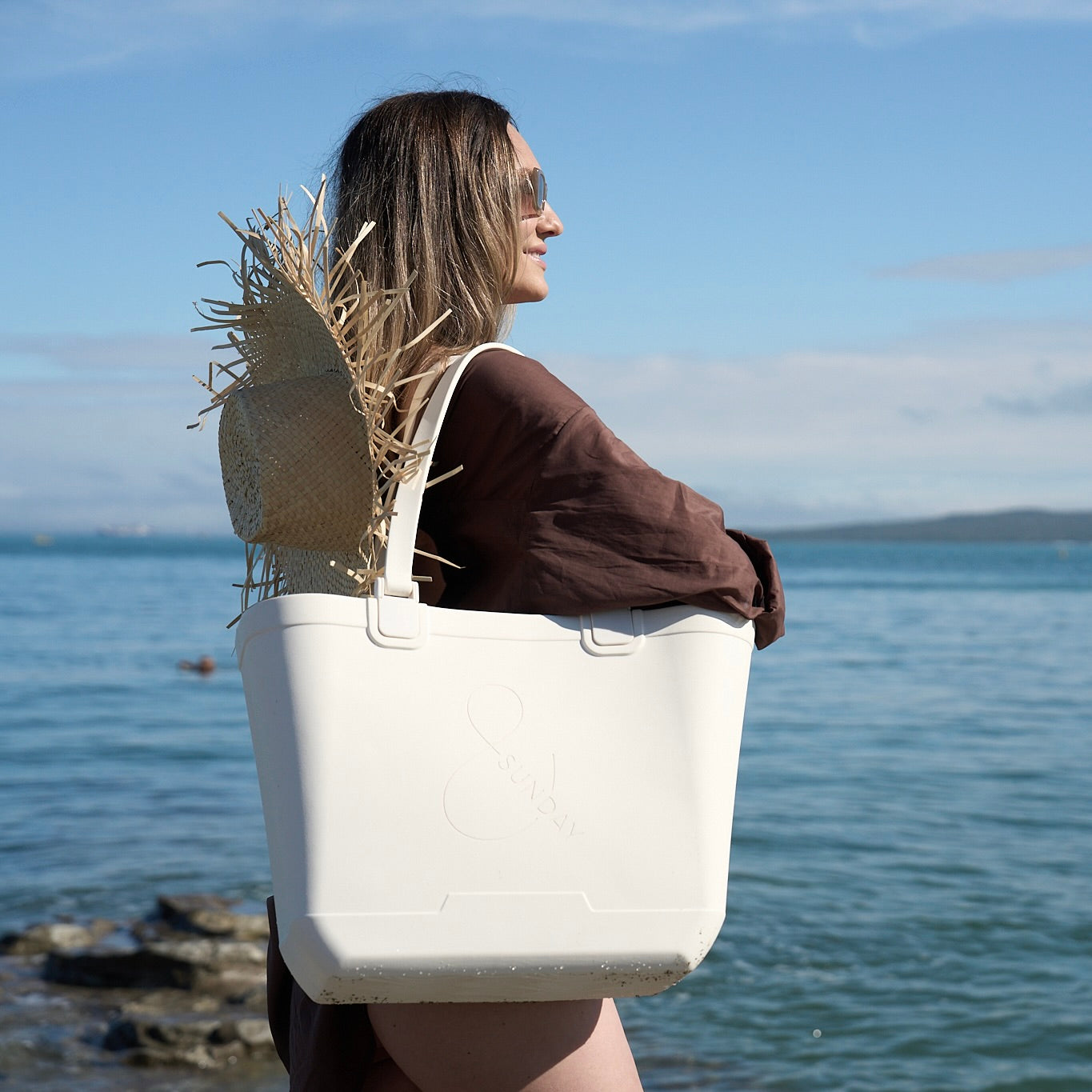 Woman holding a white waterproof tote bag by the water